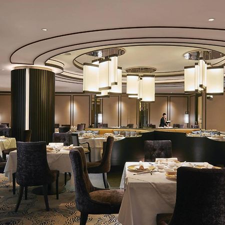 Jw Marriott Kuala Lumpur Hotel Exterior photo The image depicts a modern and elegant restaurant interior. The design features a circular ceiling with stylish light fixtures hanging down. The space is well-lit and has a sophisticated ambiance, with round tables set for dining, each covered with w