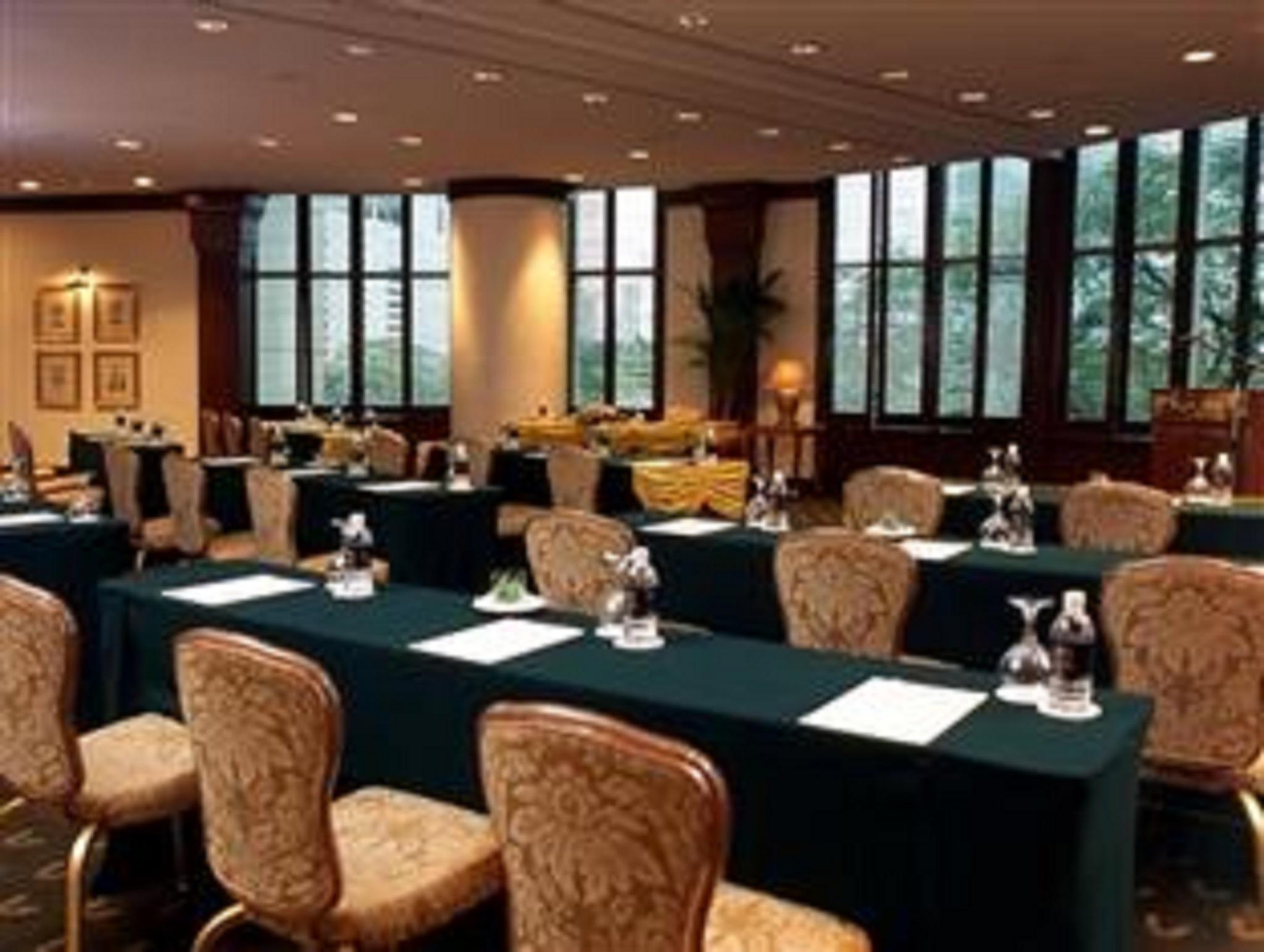 Jw Marriott Kuala Lumpur Hotel Exterior photo The photo shows a conference or meeting room setup. There are several long tables covered with dark green tablecloths and arranged in rows. Each table has a notepad and a small water pitcher, suggesting preparation for a meeting or presentation. The 
