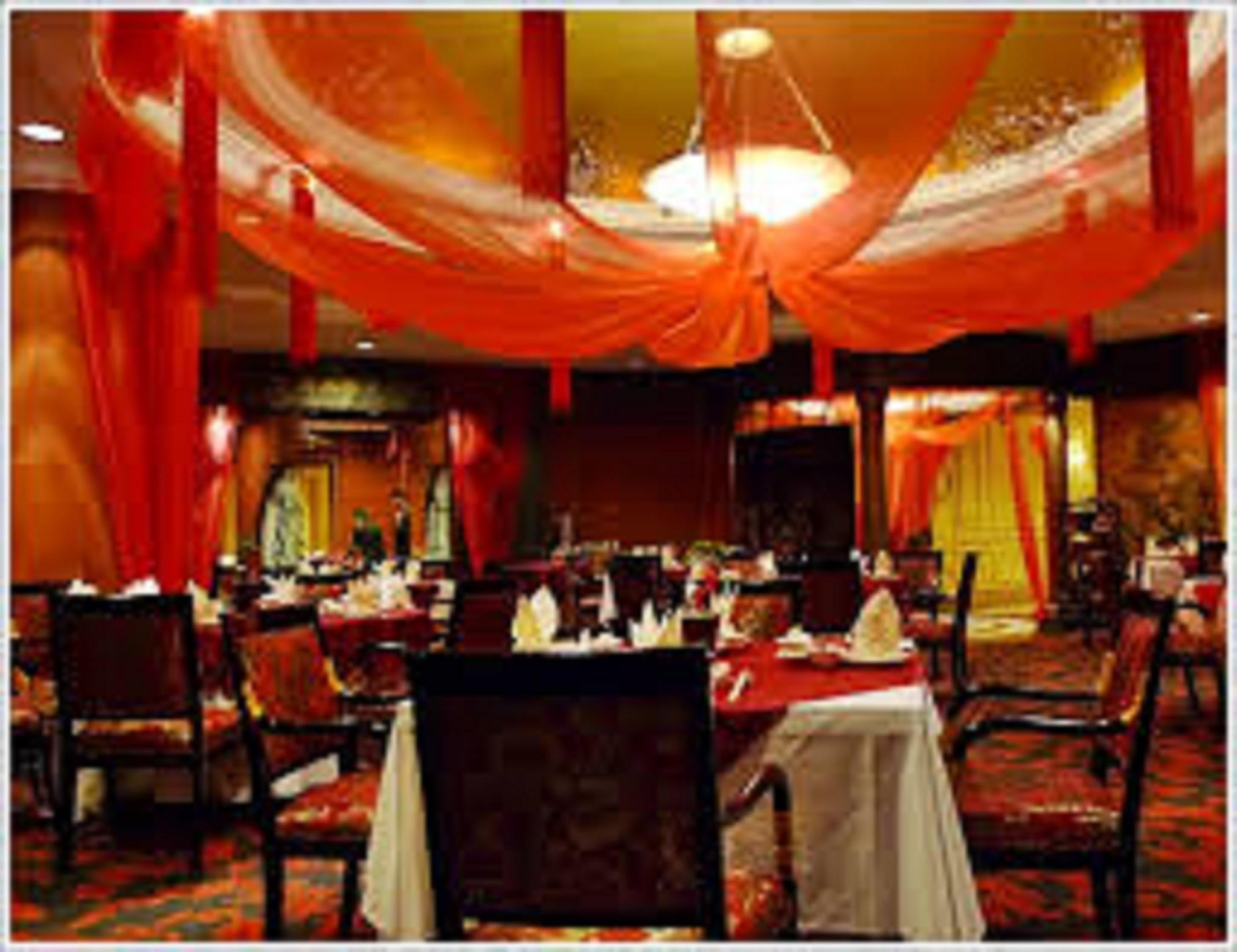 Jw Marriott Kuala Lumpur Hotel Exterior photo The photo shows an elegant dining room designed with a rich, warm color palette. The decor features draped fabric in shades of red, adding a festive and luxurious atmosphere. Several tables are set with white tablecloths and neatly arranged utensils,