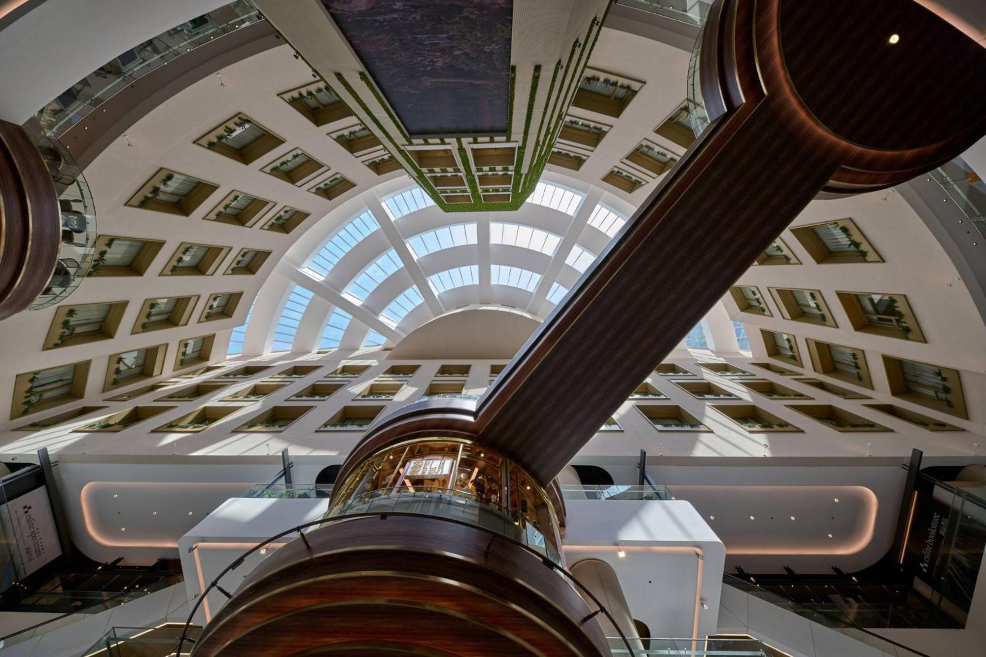 Jw Marriott Kuala Lumpur Hotel Exterior photo The image shows a modern architectural interior viewed from below, likely looking up at a large atrium or spacious lobby. The ceiling features a curved, segmented design with multiple skylights that allow natural light to flow in. There is a prominen