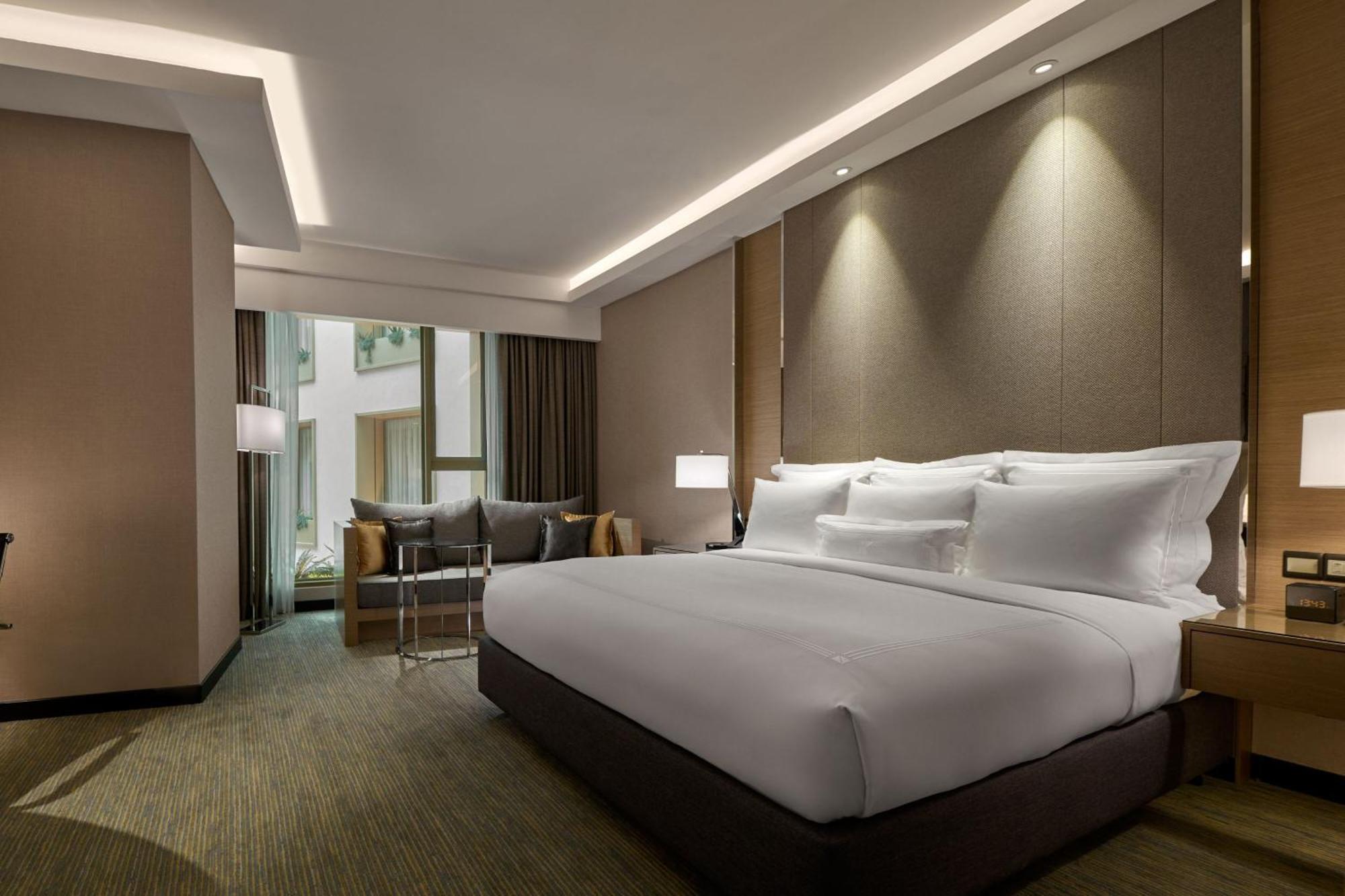 Jw Marriott Kuala Lumpur Hotel Exterior photo The photo shows a modern hotel room featuring a spacious layout. In the foreground, there is a large bed with white linens, complemented by plush pillows. The walls are decorated with a textured material, and there are soft, ambient lights enhancing 