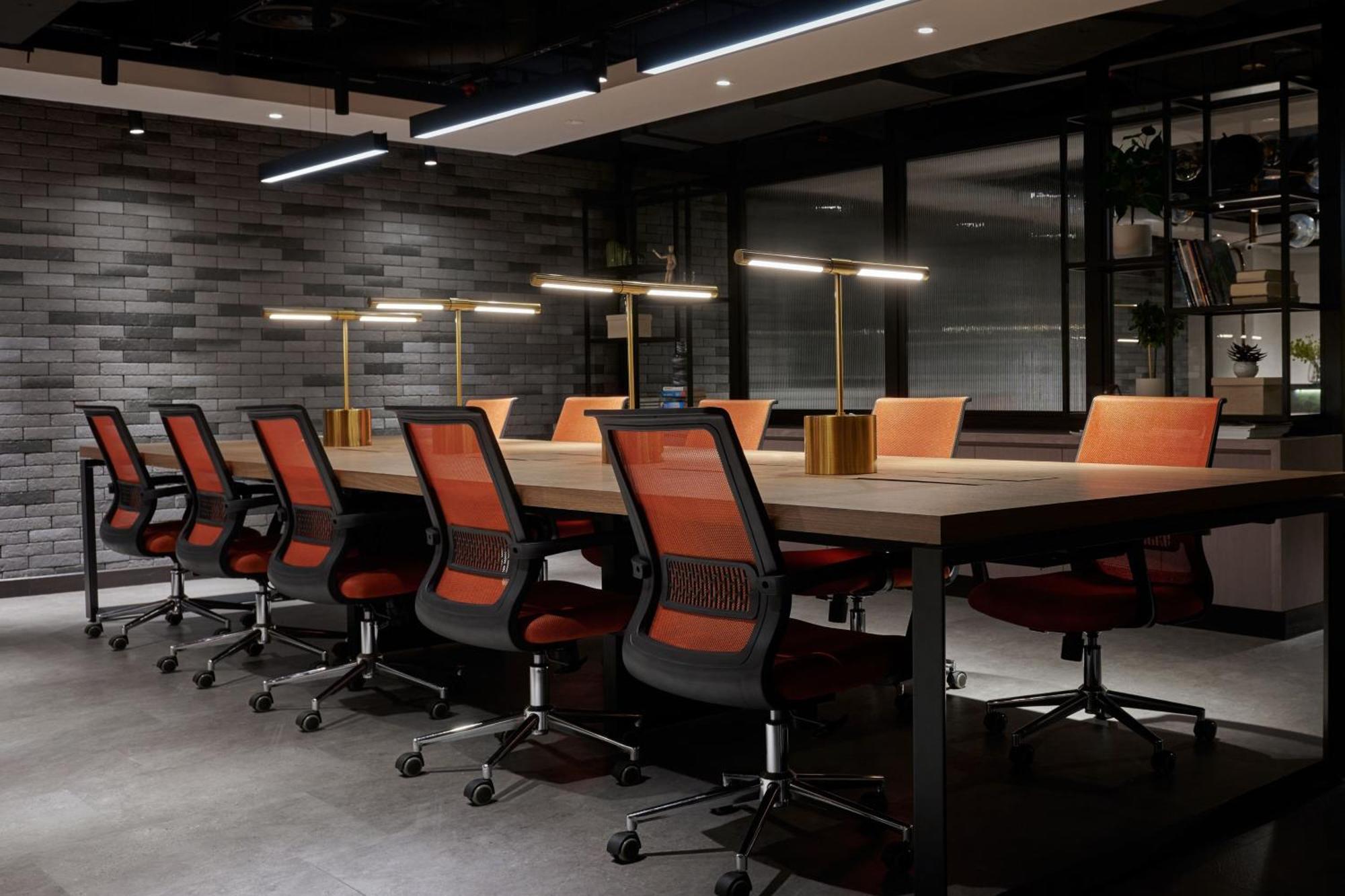 Jw Marriott Kuala Lumpur Hotel Exterior photo The photo shows a modern conference room featuring a long wooden table surrounded by several black ergonomic chairs with orange accents. Above the table, there are stylish lamp fixtures providing warm lighting. The room has a contemporary design with