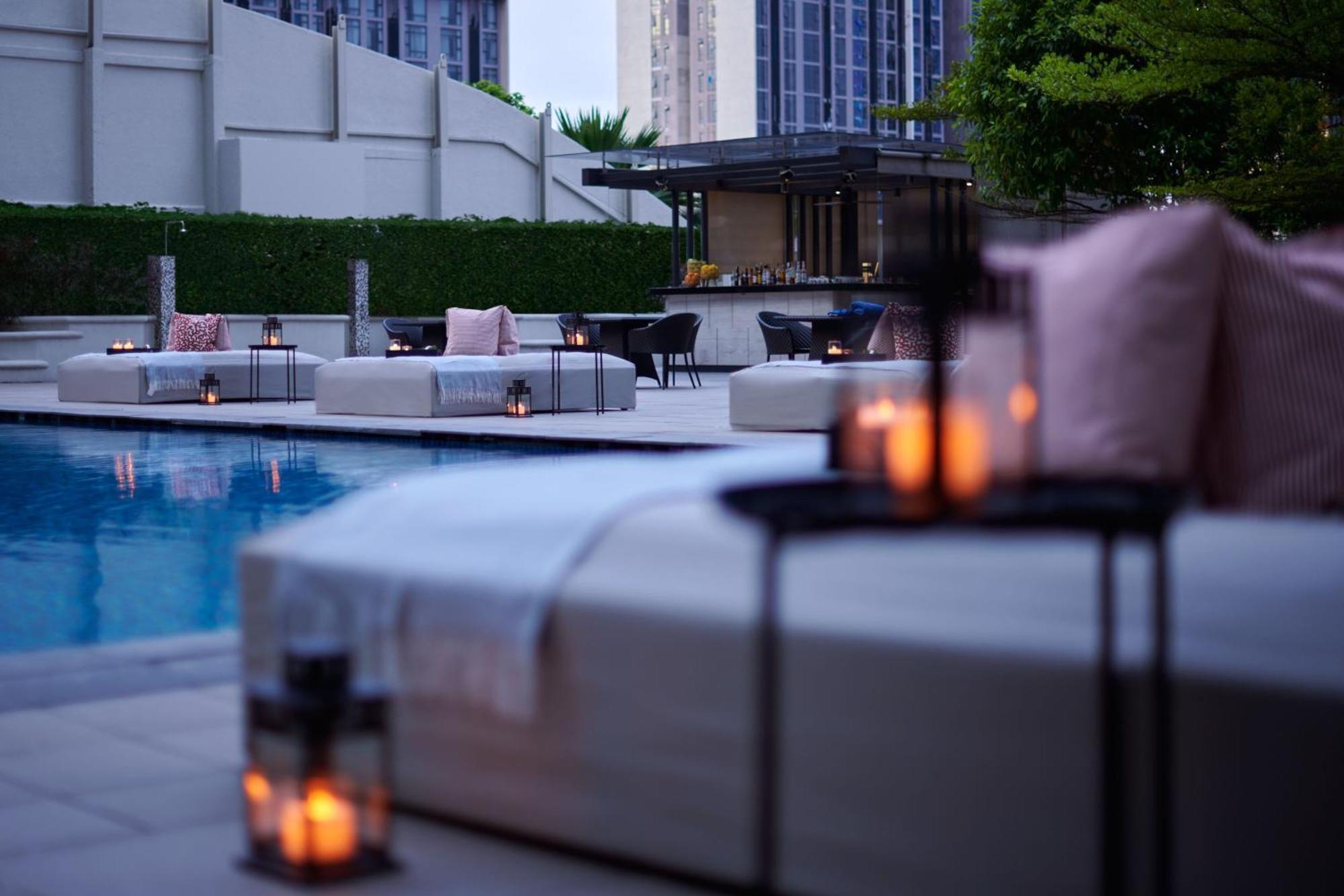 Jw Marriott Kuala Lumpur Hotel Exterior photo The photo depicts a serene outdoor pool area, featuring lounge seating arranged near the water. There are several cushioned lounges with soft pillows, as well as decorative lanterns placed on small tables, providing a warm, inviting ambiance. In the 