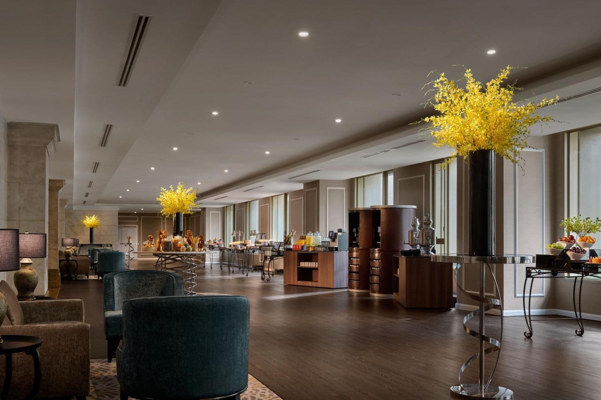 Jw Marriott Kuala Lumpur Hotel Exterior photo The photo shows the interior of a modern and elegant space, likely a hotel or restaurant lobby. The room features large windows allowing natural light to filter in, complemented by stylish lighting fixtures on the ceiling. There are several decorativ