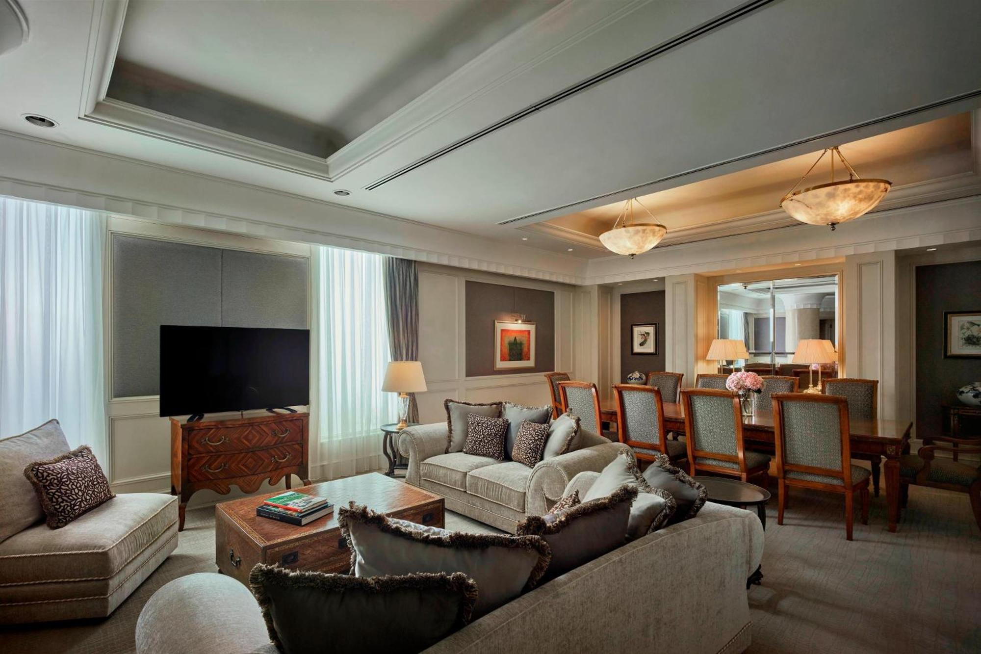 Jw Marriott Kuala Lumpur Hotel Exterior photo The photo depicts a sophisticated living room. It features a comfortable beige couch with decorative pillows and a wooden coffee table, which has some books on it. To the left, there's a large television mounted on a wall. Natural light filters in th