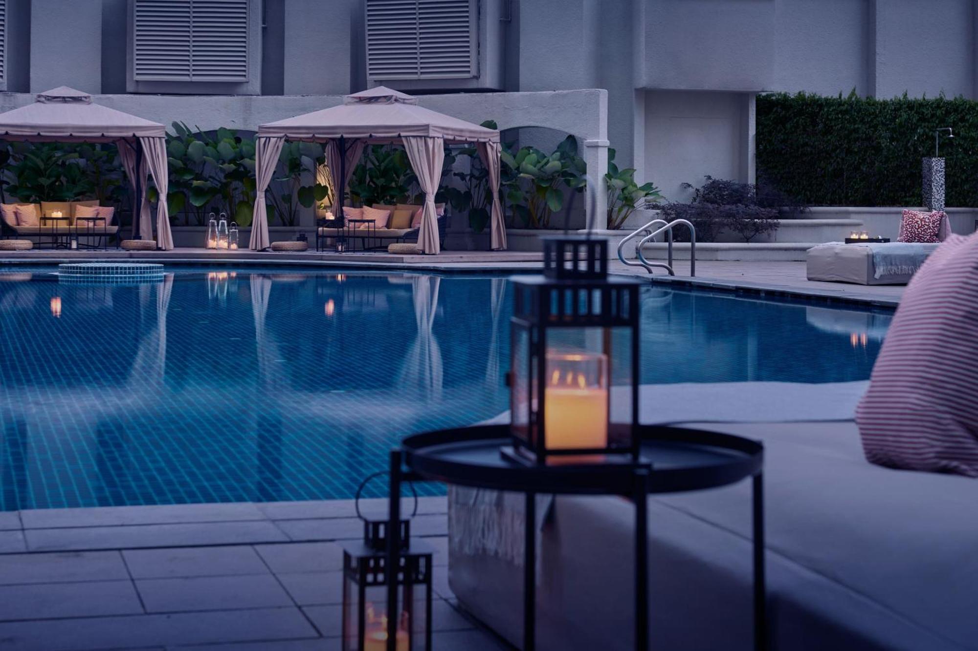 Jw Marriott Kuala Lumpur Hotel Exterior photo The photo depicts a luxurious outdoor area featuring a swimming pool. Surrounding the pool are elegant cabanas with soft fabric drapes. The atmosphere is tranquil and inviting, enhanced by soft lighting from lanterns placed on a nearby table. The poo