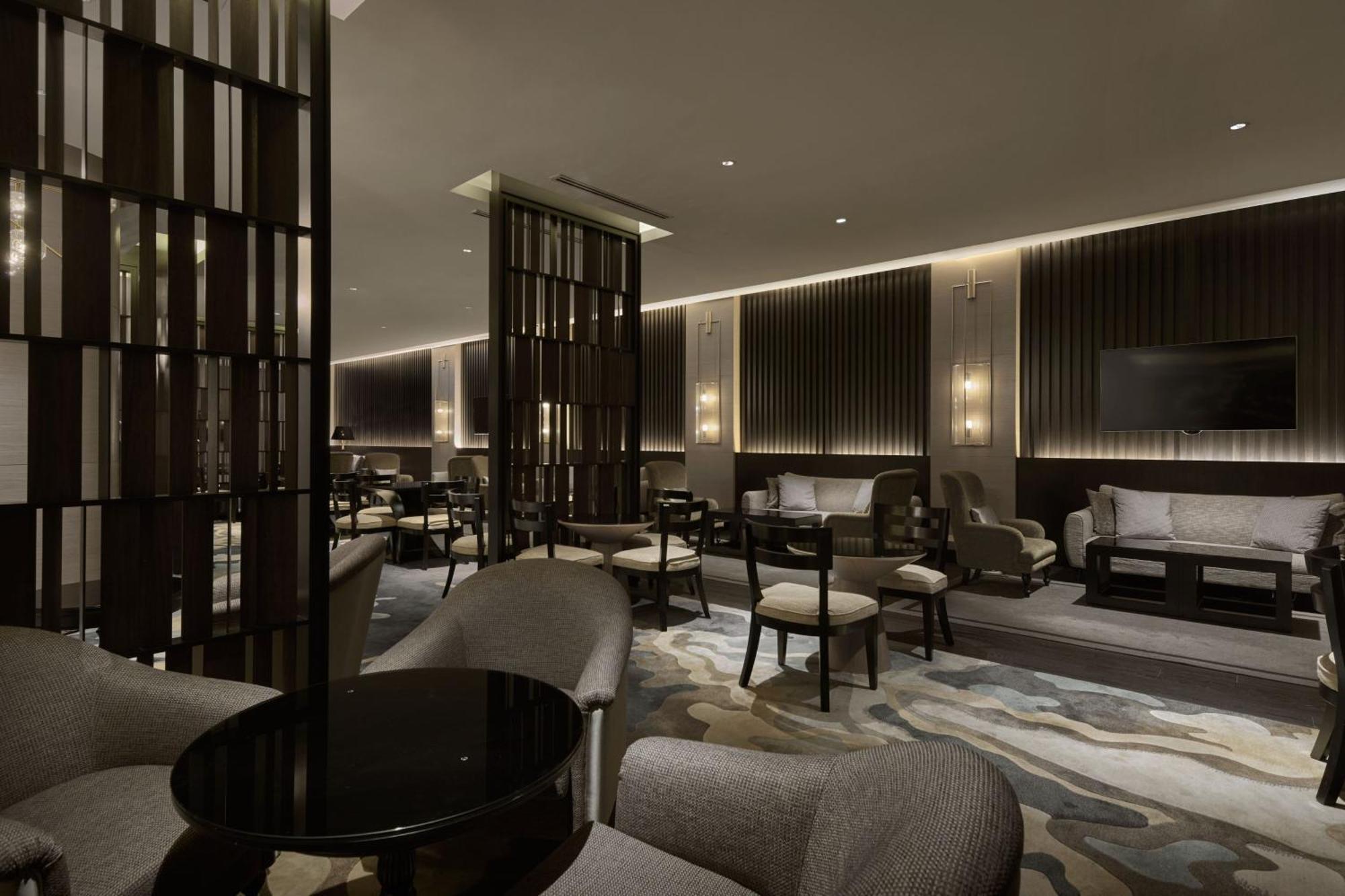 Jw Marriott Kuala Lumpur Hotel Exterior photo The photo shows a modern, elegantly designed lounge area. It features a combination of comfortable seating arrangements, including plush chairs and sofas. There are dark wooden dividers that provide a sense of separation between different sections of