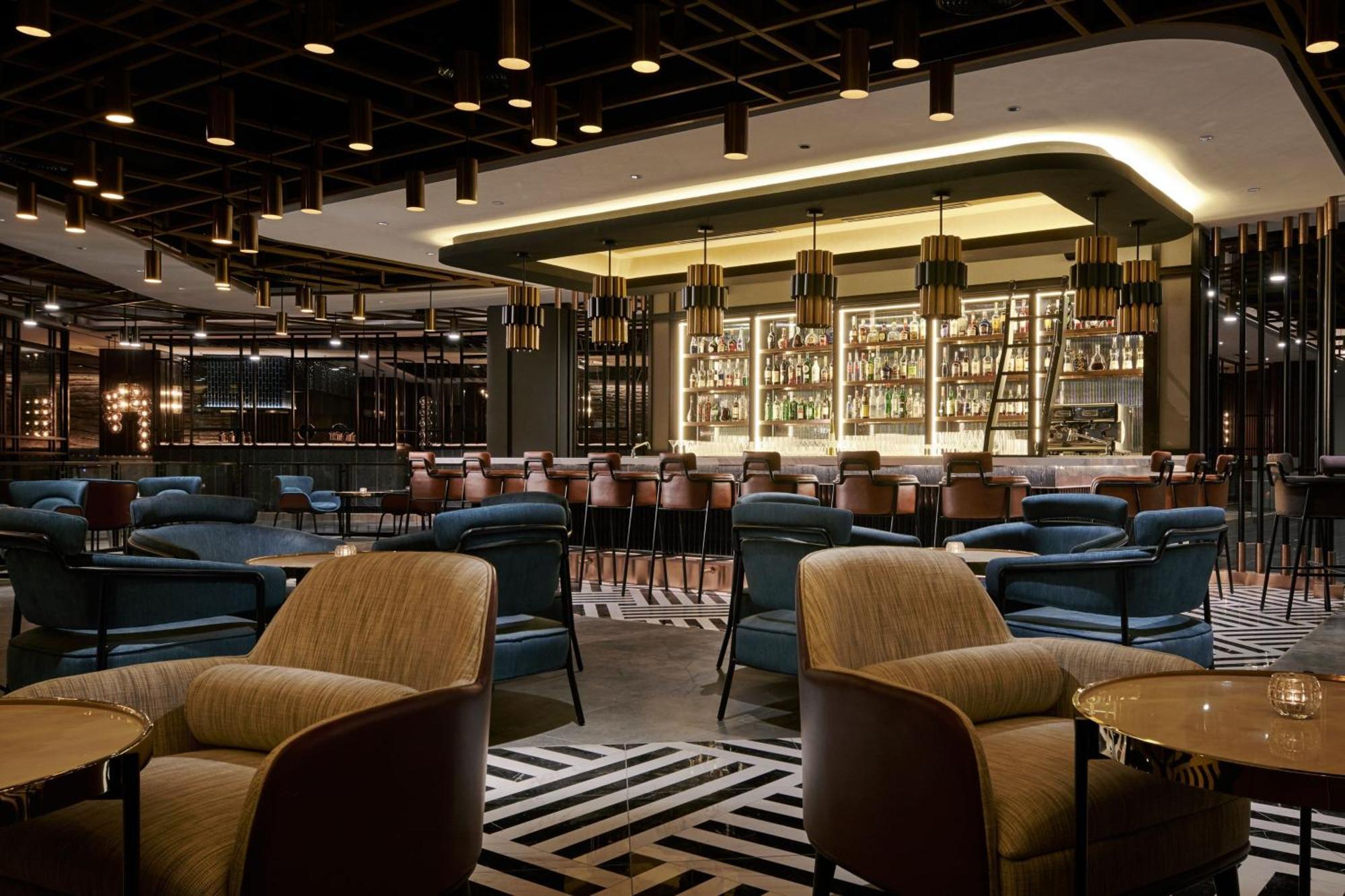 Jw Marriott Kuala Lumpur Hotel Exterior photo The photo depicts an elegant bar or lounge area inside a modern restaurant. The space features a stylish design with a combination of seating options, including plush armchairs and bar stools. The bar is well-stocked with a variety of bottles display