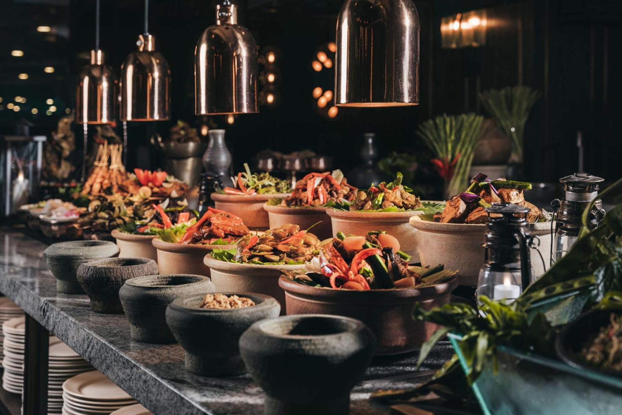 Jw Marriott Kuala Lumpur Hotel Exterior photo The photo displays a beautifully arranged buffet or dining setup featuring a variety of dishes. There are several clay or stone bowls filled with colorful, freshly prepared food items, likely including salads, vegetables, and proteins. The setting ha