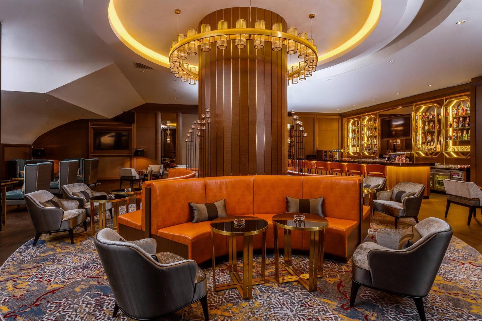 Jw Marriott Kuala Lumpur Hotel Exterior photo The photo depicts a stylish and modern lounge area. At the center, there is a large, circular fixture with pendant lighting hanging from the ceiling, creating an elegant atmosphere. Surrounding this centerpiece are cozy seating arrangements, includin
