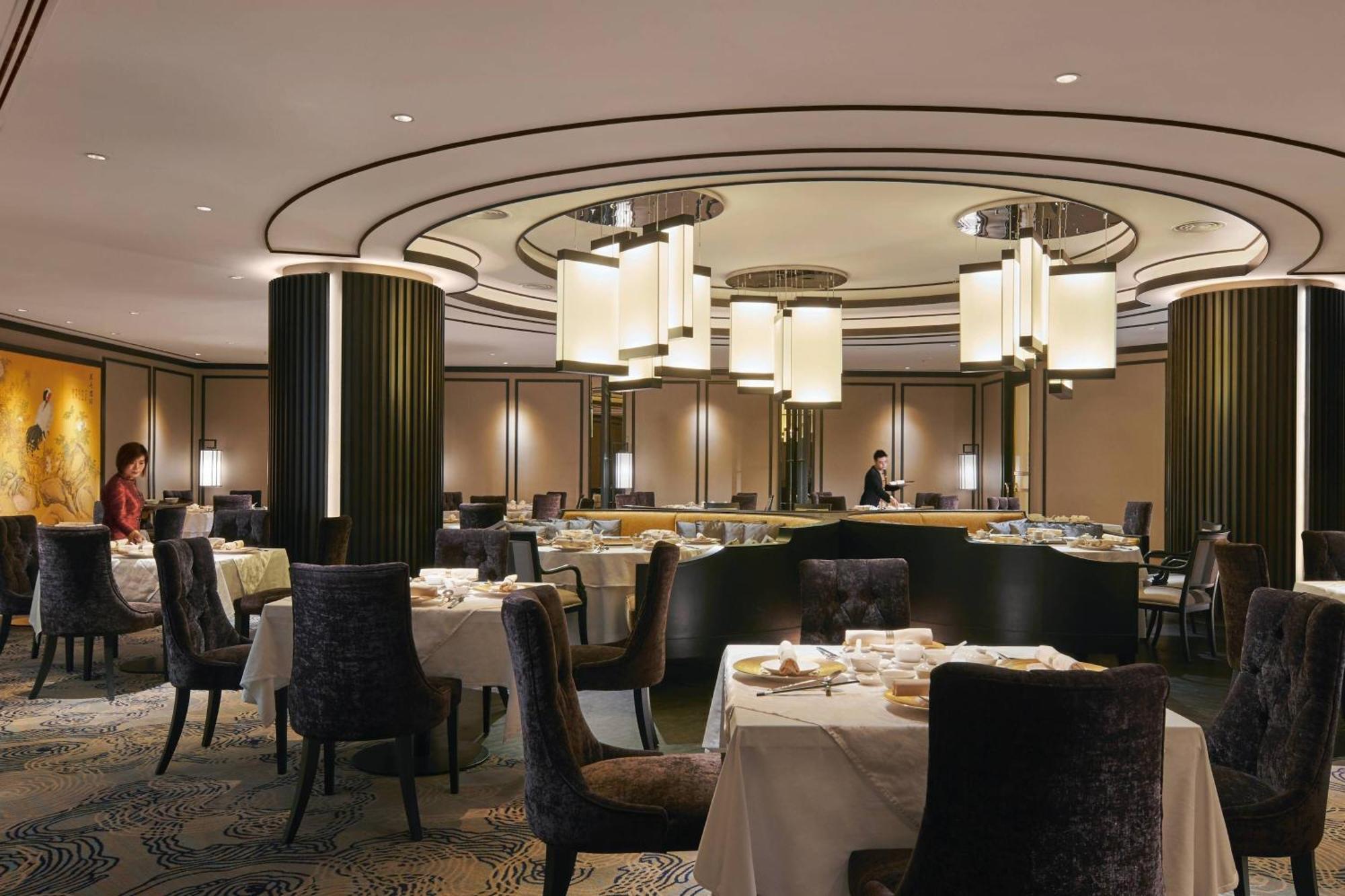 Jw Marriott Kuala Lumpur Hotel Exterior photo The image depicts a modern and elegant restaurant interior. The design features a circular ceiling with stylish light fixtures hanging down. The space is well-lit and has a sophisticated ambiance, with round tables set for dining, each covered with w